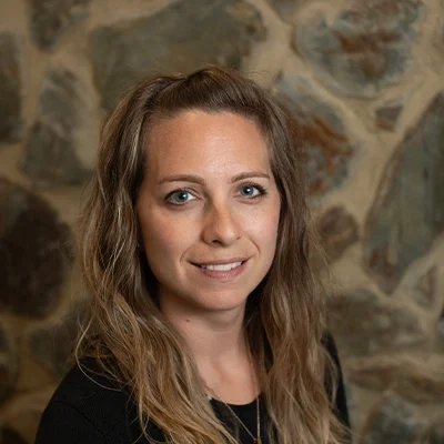 Chiropractor Gloria Outlaw Smiling In Front Of Cobble Wall