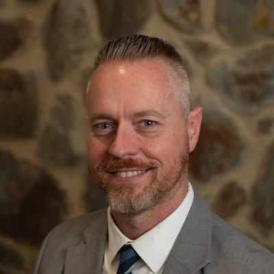 Chiropractor Rick Hulse Smiling In Front Of Cobble Wall