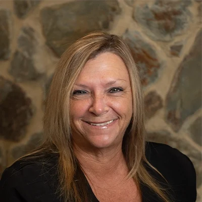 Shelia Smiling In Front Of Cobble Wall